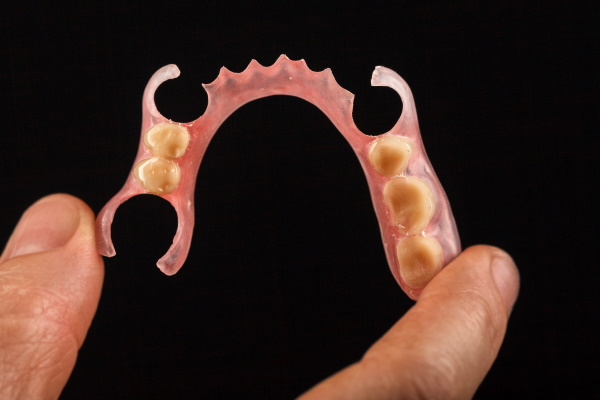 Dental prosthesis in the hand of the dentist. Close-up on a black background